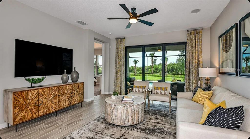 A living room features a wooden console, a round coffee table, and sliding glass doors — 737 STEEL DRIVE, APOLLO BEACH, FL