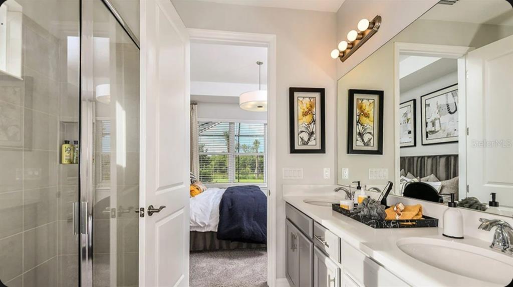 A bathroom with a glass shower, gray vanity, and a doorway leading into a bedroom — 737 STEEL DRIVE, APOLLO BEACH, FL