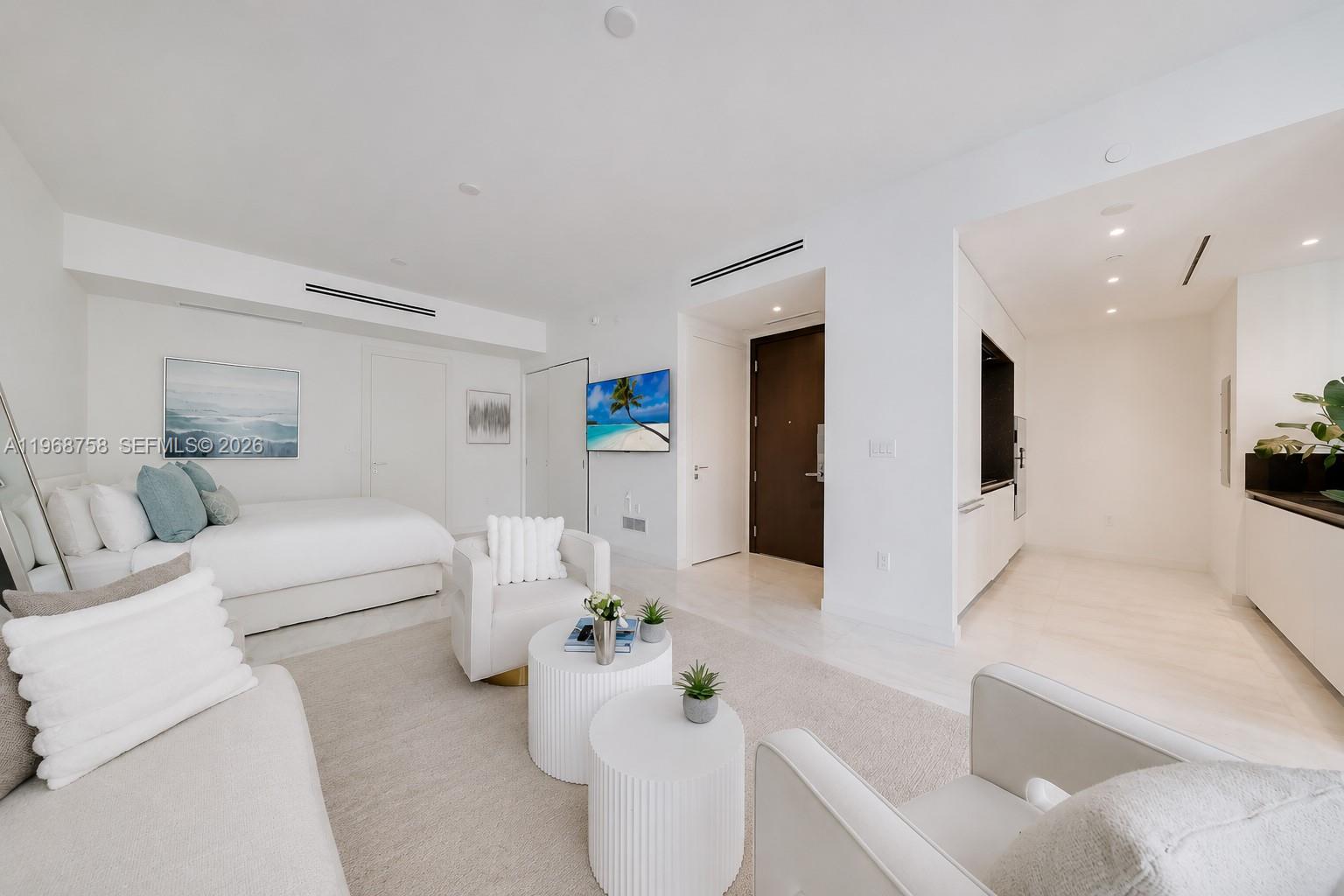 A modern studio apartment features a bed, seating area, and kitchenette with white finishes — 300 Biscayne Boulevard Way # 1105C, Miami FL 33131, MIAMI, FL