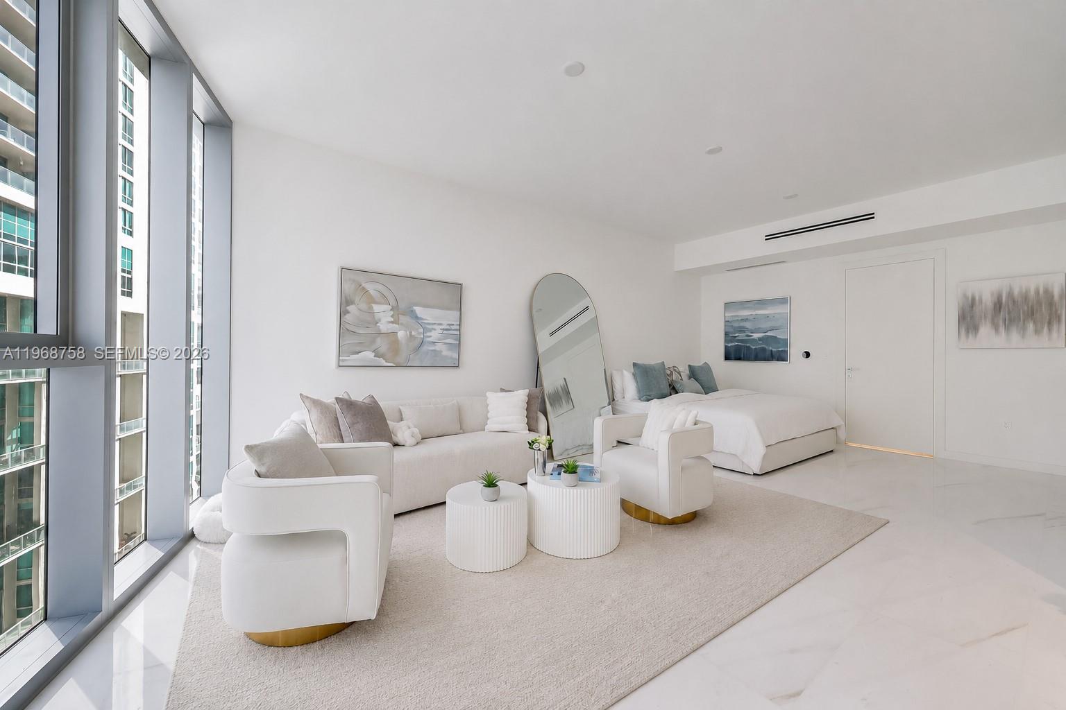 A modern studio apartment features a living area, bed, white furniture, and floor-to-ceiling windows — 300 Biscayne Boulevard Way # 1105C, Miami FL 33131, MIAMI, FL