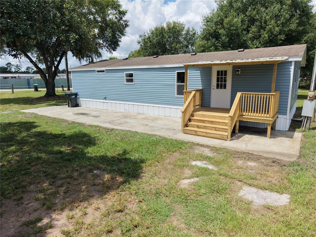 A blue mobile home features a wooden porch, stairs, and a concrete patio area — 18577 EVERETT RD, ORLANDO, FL