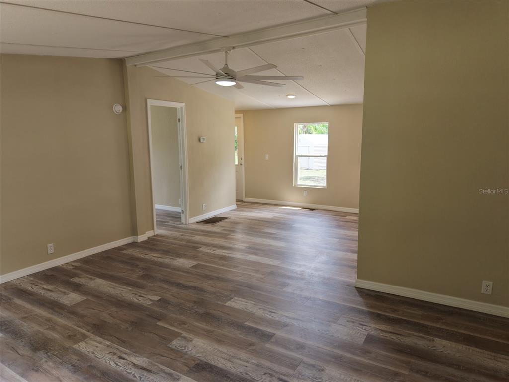 An interior view of a living area with light-colored walls and wood-look laminate flooring — 18577 EVERETT RD, ORLANDO, FL