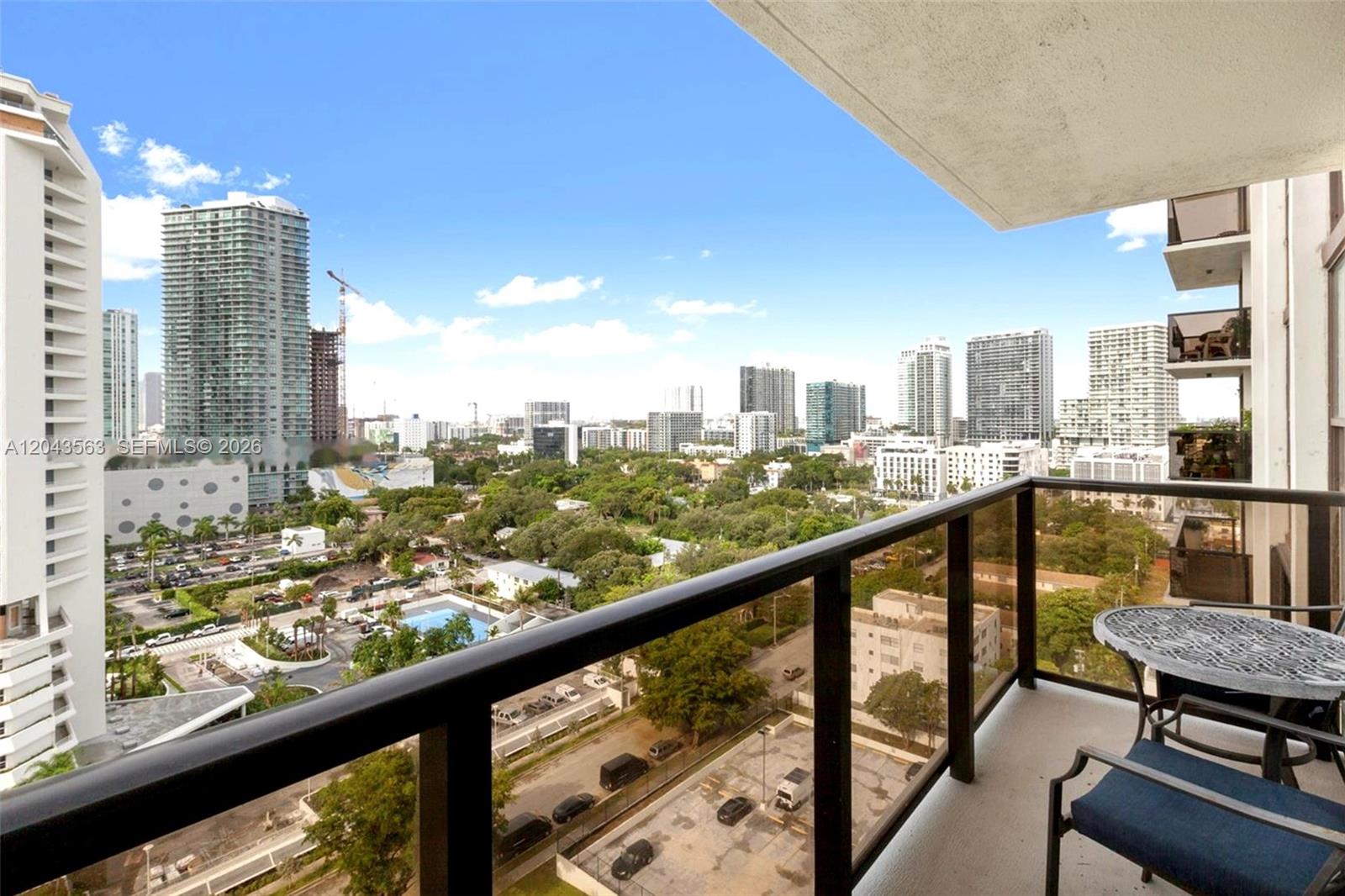 A balcony with a glass railing overlooks a city skyline and a parking lot — 600 NE 36th St # 1717, Miami FL 33137, MIAMI, FL