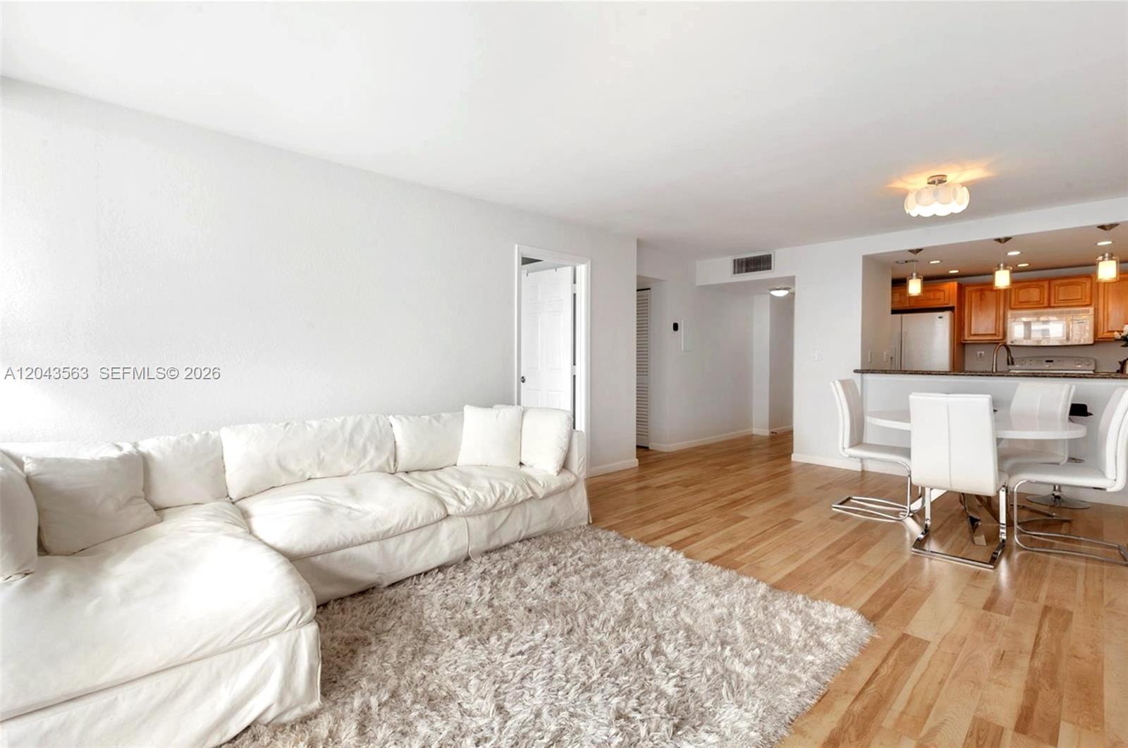 A white sectional sofa sits on a rug in a living room with hardwood floors — 600 NE 36th St # 1717, Miami FL 33137, MIAMI, FL