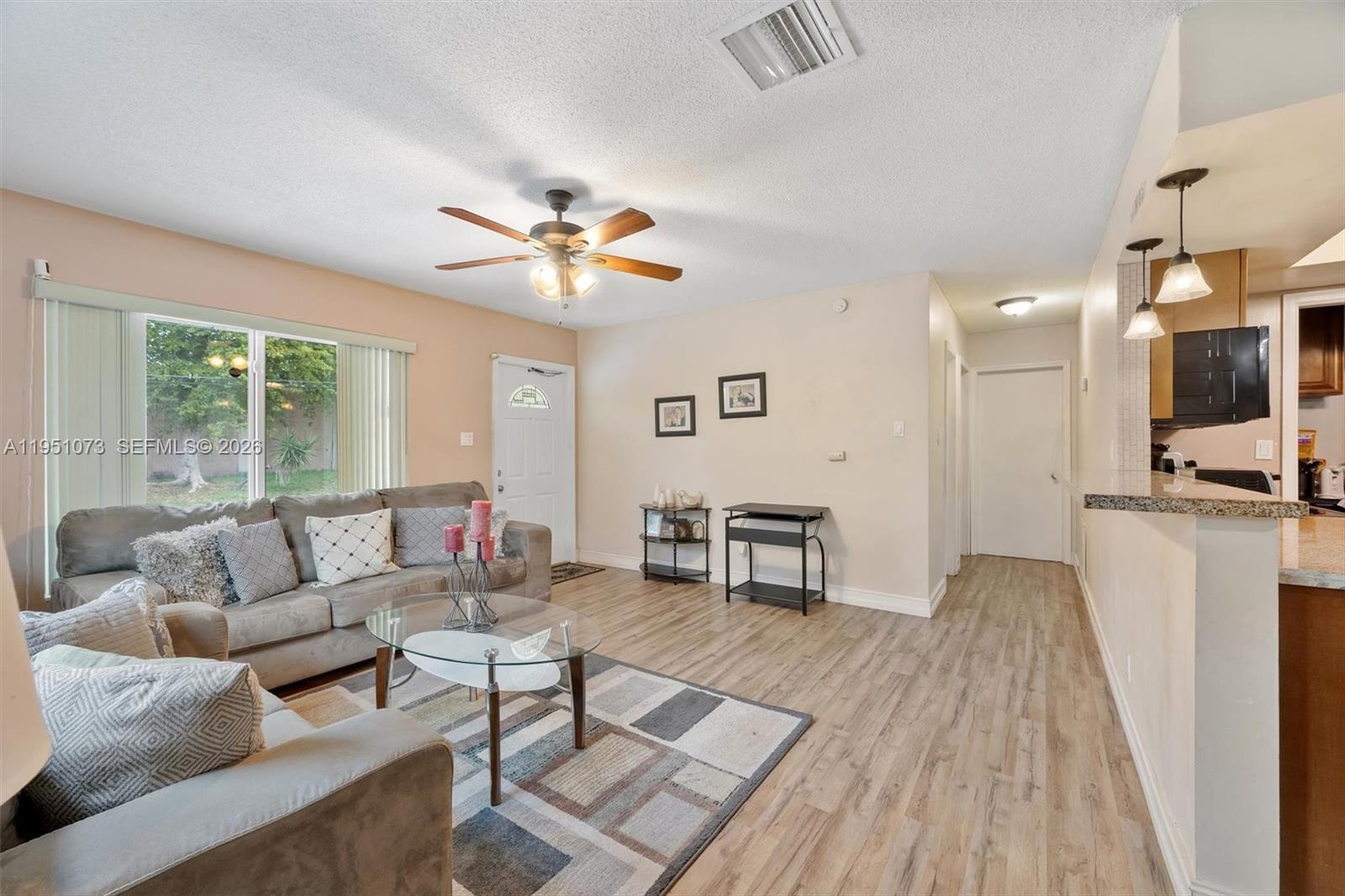 A living room features light-colored walls, wood-look flooring, two gray sofas, and a ceiling fan — 4714 NW 50th Ct, Tamarac FL 33319, TAMARAC, FL