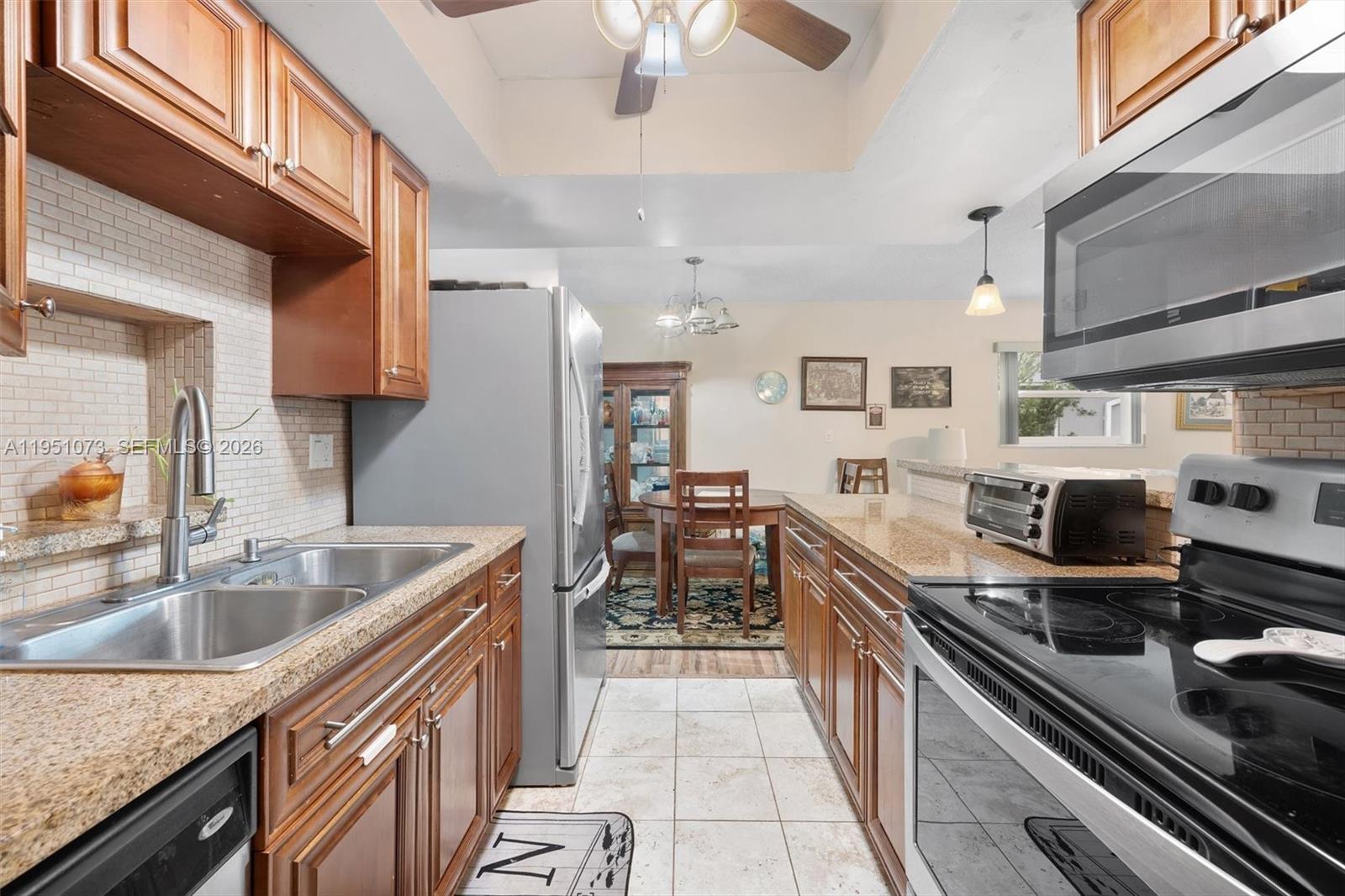 A bedroom features a wooden bed frame, a television on a stand, and wood-look flooring — 4714 NW 50th Ct, Tamarac FL 33319, TAMARAC, FL
