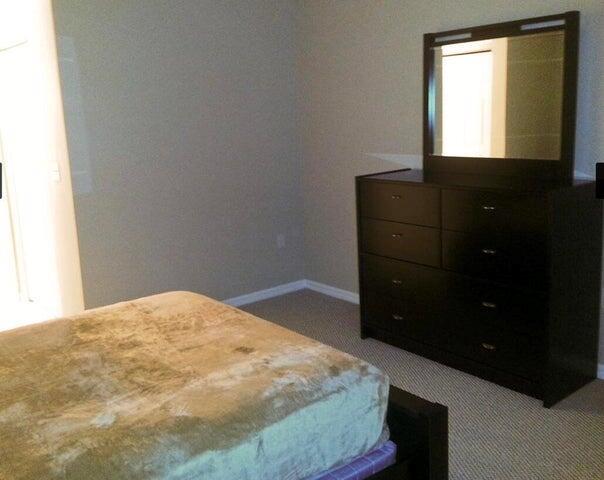 A bedroom features a dark wood dresser with a mirror and a bed with a blanket — 804 E Windward Way # 119, Lantana FL 33462, LANTANA, FL