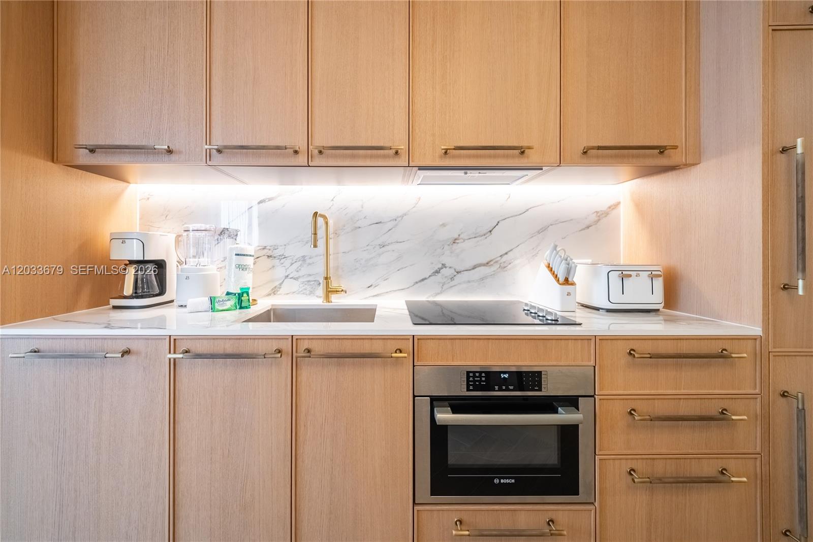 A modern kitchen features light wood cabinetry, a marble backsplash, and gold-toned hardware — 2700 NW 2nd Ave # 237, Miami FL 33127, MIAMI, FL