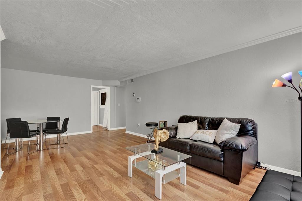 A living room with wood-look flooring, a black leather sofa, and a glass coffee table — 1940 CONWAY UNIT 8, ORLANDO, FL