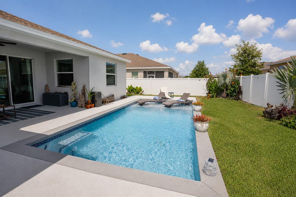 A rectangular swimming pool with lounge chairs sits on a patio beside a suburban house — 5795 SW 80TH LANE, OCALA, FL