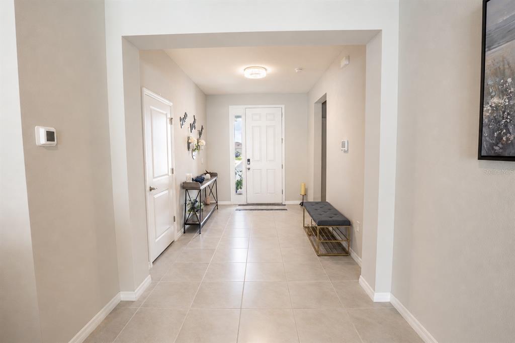 A bright entryway features light tile flooring, a white front door, and a bench — 5795 SW 80TH LANE, OCALA, FL