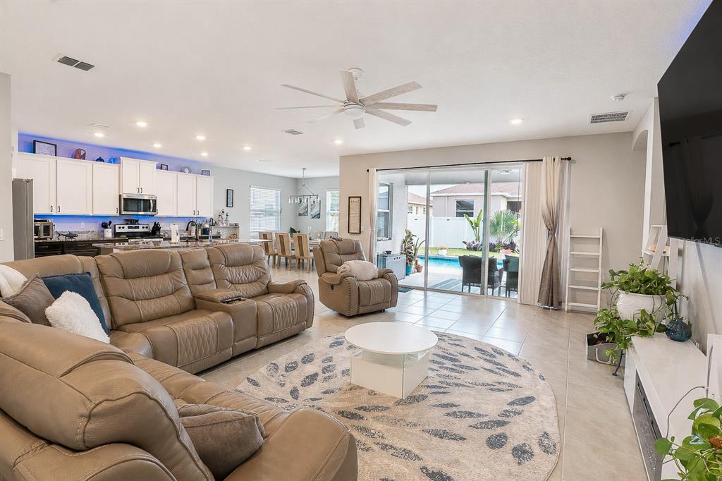 A living room with a tan sectional, recliner, and sliding glass doors opening to a pool — 5795 SW 80TH LANE, OCALA, FL
