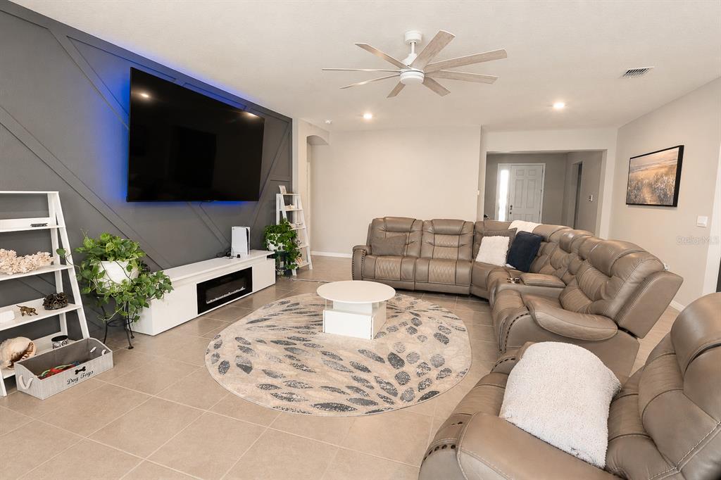 A living room features a large gray sectional sofa, a circular rug, and a television wall — 5795 SW 80TH LANE, OCALA, FL