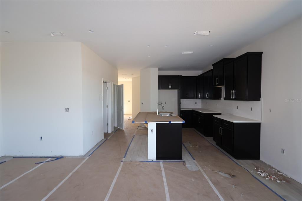 A kitchen under construction features dark cabinets, white countertops, and a central island with sink — 5192 CENTER LAKE RANCH BOULEVARD, ST CLOUD, FL