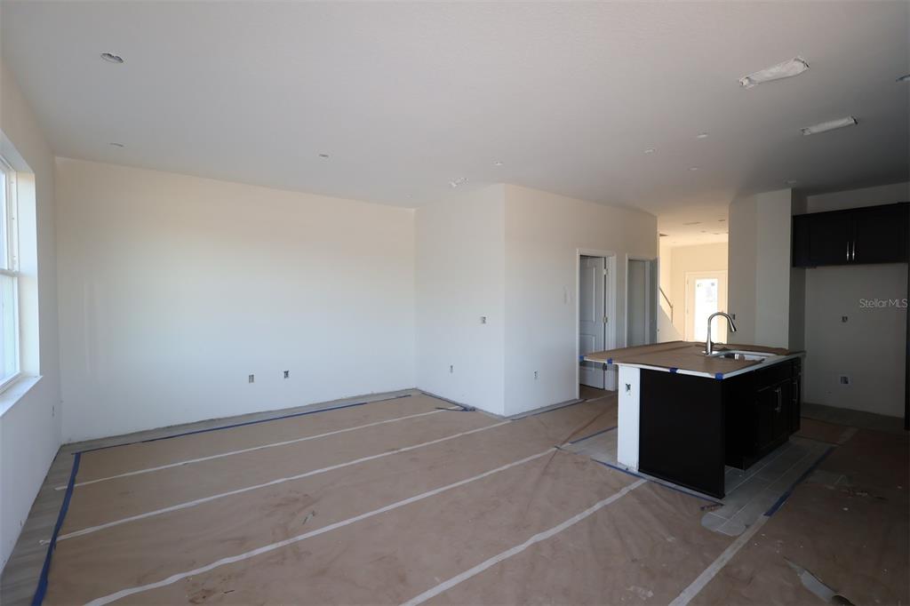 An unfinished room features a kitchen island with a sink and dark cabinetry — 5192 CENTER LAKE RANCH BOULEVARD, ST CLOUD, FL