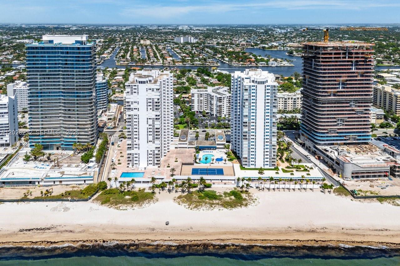 An aerial view shows four high-rise buildings along a sandy beach with swimming pools below — 1370 S Ocean Blvd # 1206, Pompano Beach FL 33062, POMPANO BEACH, FL