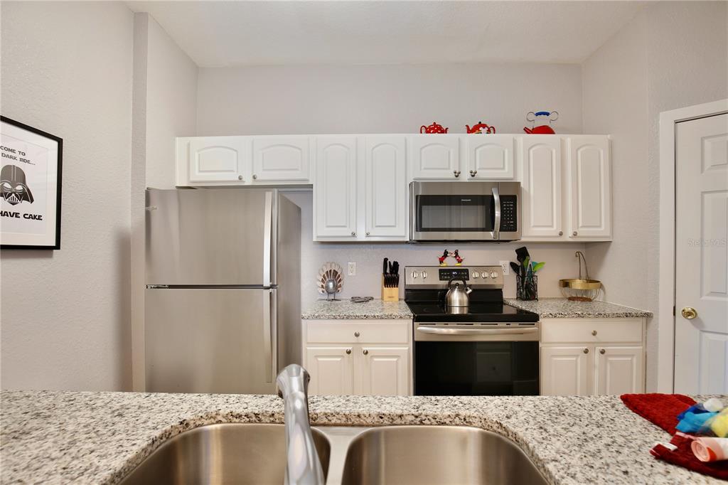 A kitchen features stainless steel appliances, white cabinets, and granite countertops — 2821 ALMATON LOOP UNIT 301, KISSIMMEE, FL