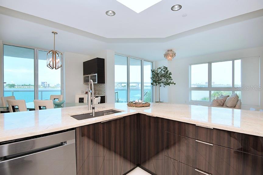A modern kitchen features dark wood cabinetry, a light stone countertop, and floor-to-ceiling windows — 231 RIVERSIDE DRIVE UNIT 301-1, HOLLY HILL, FL