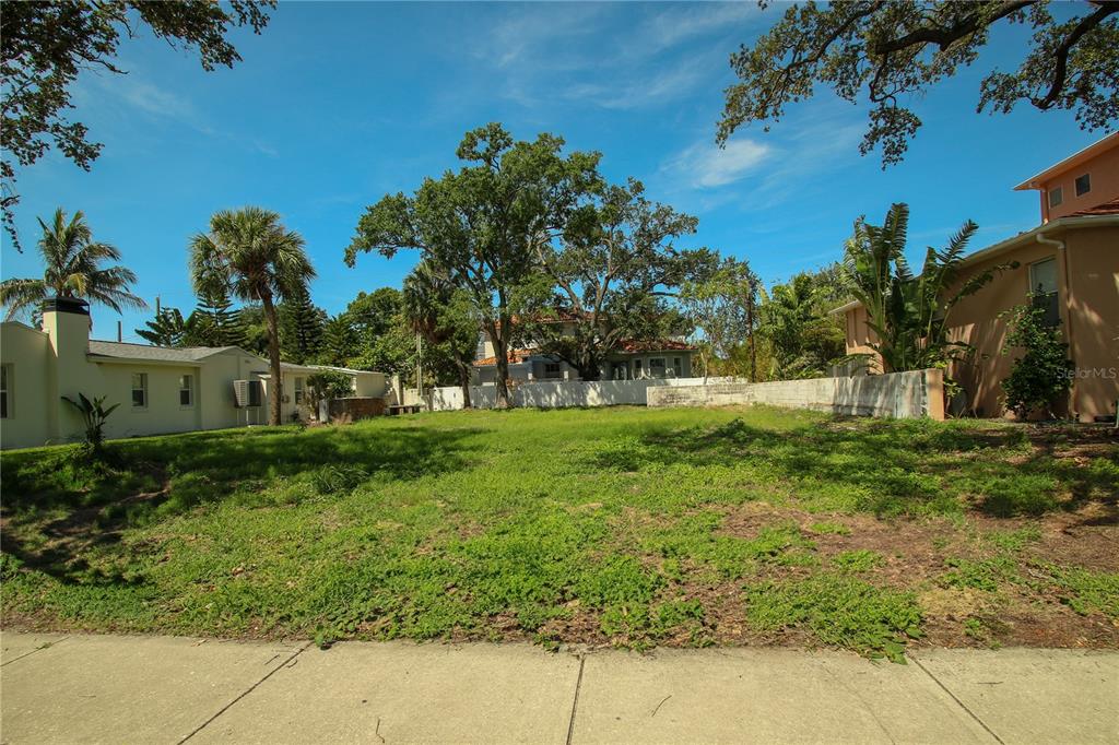 A vacant, grassy residential lot sits between two existing houses under a blue sky — 424 CHANNEL DRIVE, TAMPA, FL