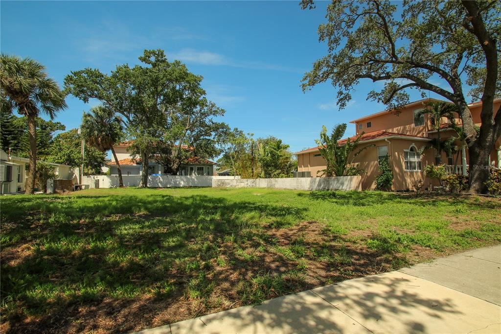 A vacant, grassy residential lot is bordered by mature trees and neighboring houses — 424 CHANNEL DRIVE, TAMPA, FL