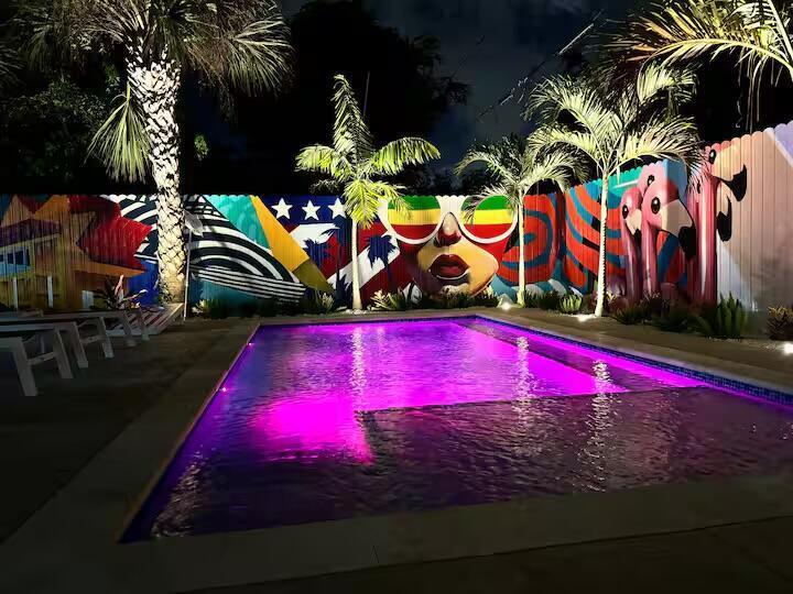 A swimming pool with purple underwater lighting sits in front of a colorful mural wall — 322 NW 4th Avenue, Delray Beach FL 33444, DELRAY BEACH, FL