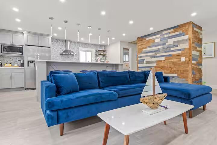 A blue velvet sectional sofa sits in a living room with a wood-accented wall — 322 NW 4th Avenue, Delray Beach FL 33444, DELRAY BEACH, FL