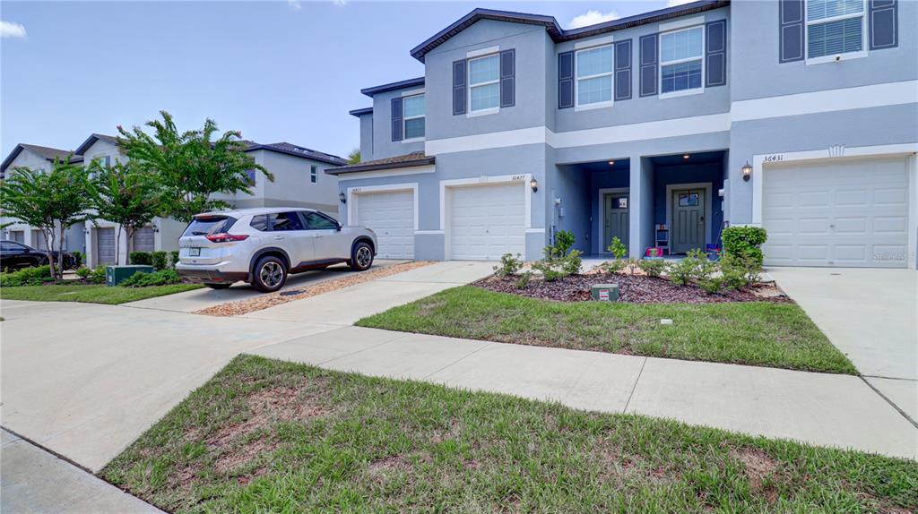 A silver SUV is parked in the driveway of a two-story suburban townhome — 36427 GARDEN WALL WAY, ZEPHYRHILLS, FL
