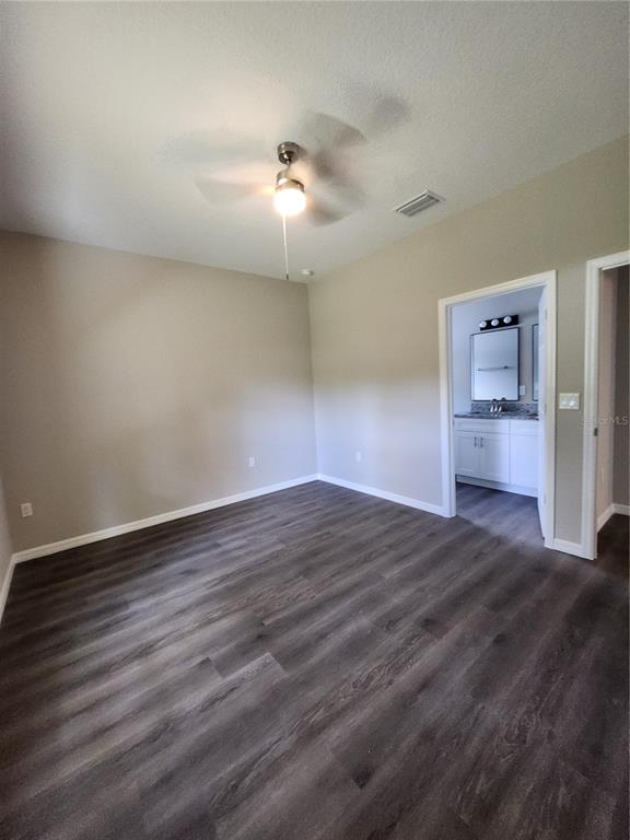 A bedroom with gray wood-look flooring, a ceiling fan, and an attached bathroom — 5016 FINDERS COURT, TAMPA, FL