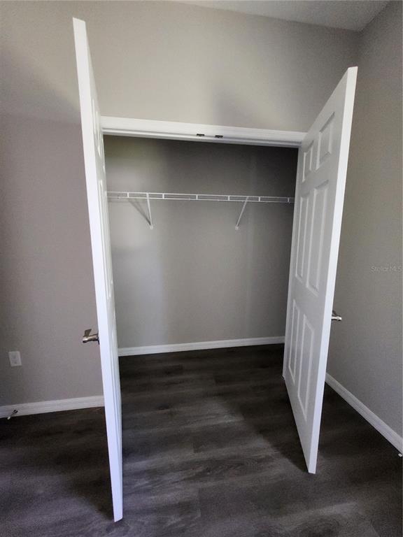 A closet with white double doors, a wire shelf, and dark wood-look flooring — 5016 FINDERS COURT, TAMPA, FL