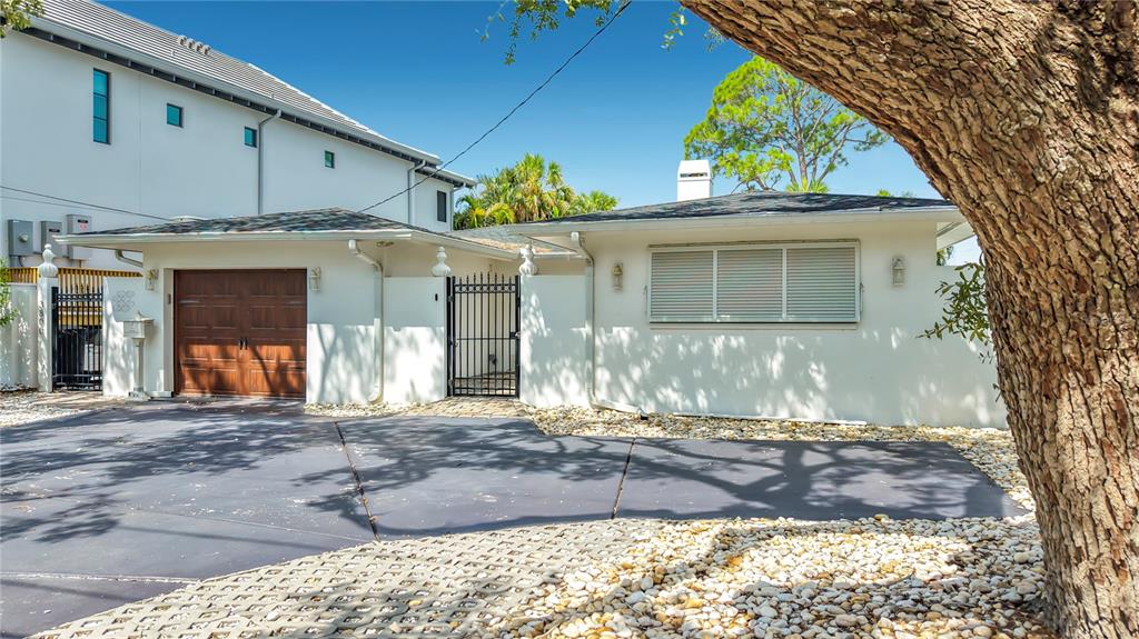A white single-story house with a wooden garage door and a black metal gate — 3800 SHORE ACRES BOULEVARD NE, ST PETERSBURG, FL