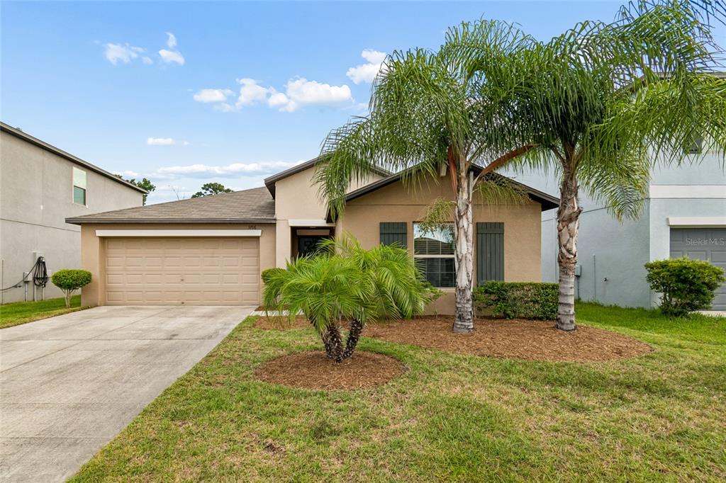 A single-story house with a tan stucco exterior, a two-car garage, and two palm trees — 3706 CAT MINT STREET, TAMPA, FL