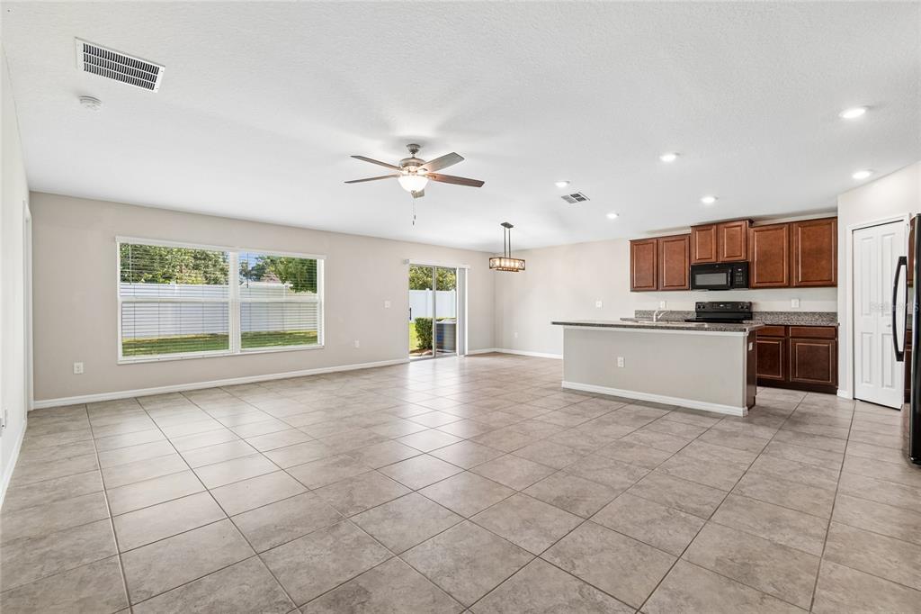 An open-concept kitchen and living area features tile flooring, dark wood cabinets, and sliding doors — 3706 CAT MINT STREET, TAMPA, FL