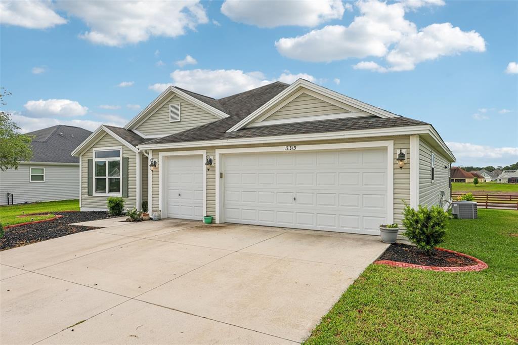 A single-story house with light green siding, a two-car garage, and a concrete driveway — 3315 DZURO DRIVE, OXFORD, FL