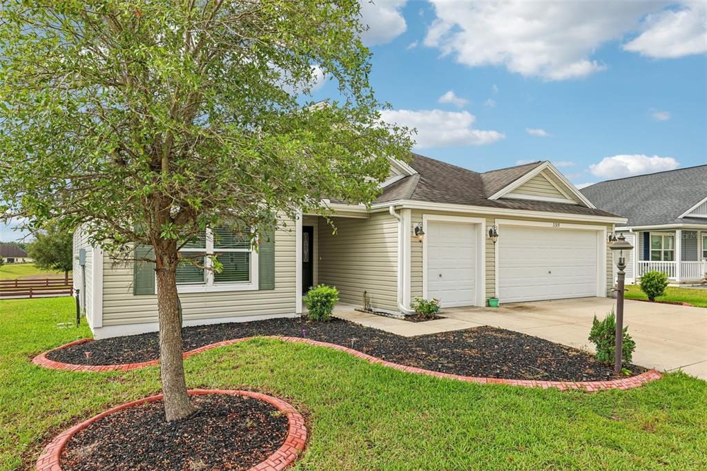 A single-story house with light siding, a two-car garage, and a landscaped front yard — 3315 DZURO DRIVE, OXFORD, FL