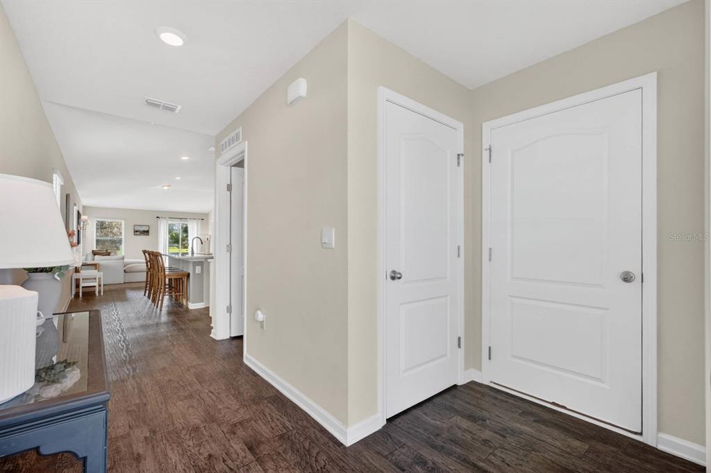 A hallway with wood-look flooring leads to an open-concept kitchen and living area — 760 GRAND RESERVE DRIVE, BUNNELL, FL