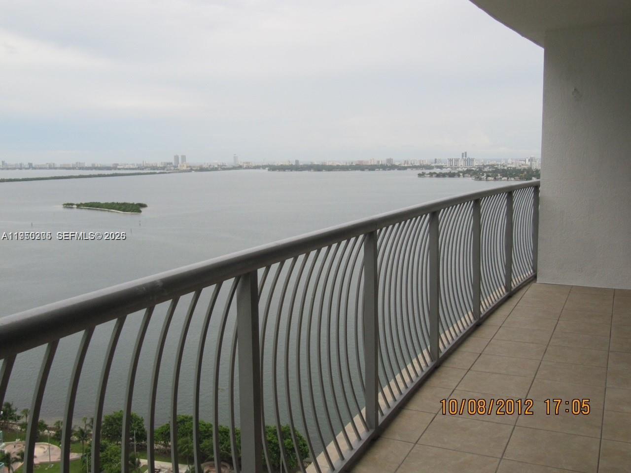 A balcony with a metal railing overlooks a large body of water and a city skyline — 1750 N Bayshore Dr # 3005, Miami FL 33132, MIAMI, FL