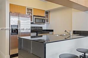 A modern kitchen features stainless steel appliances, light wood cabinets, and a black countertop island — 1750 N Bayshore Dr # 3005, Miami FL 33132, MIAMI, FL