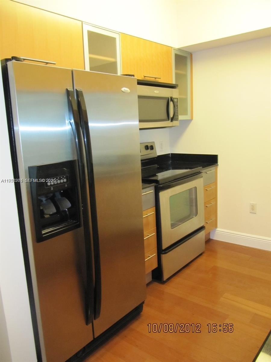 A kitchen features stainless steel appliances, light wood cabinets, and dark countertops over hardwood floors — 1750 N Bayshore Dr # 3005, Miami FL 33132, MIAMI, FL
