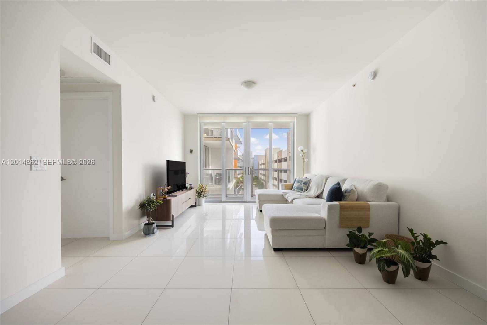A bright living room features white tile floors, a sectional sofa, and a glass balcony door — 7825 NW 107th Ave # 419, Doral FL 33178, DORAL, FL
