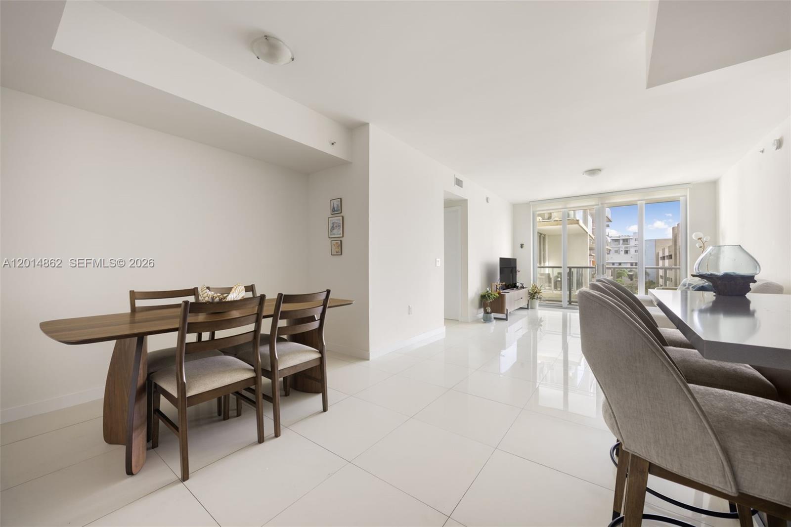 A dining area with a wooden table and chairs sits adjacent to a living space — 7825 NW 107th Ave # 419, Doral FL 33178, DORAL, FL