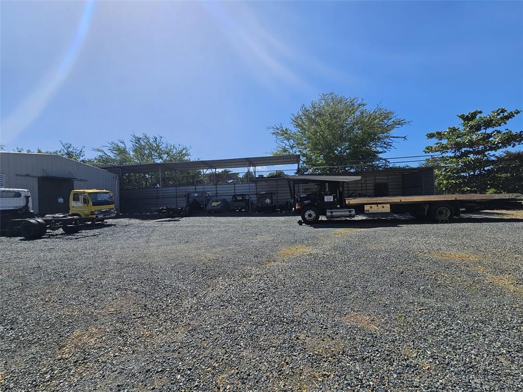 A gravel lot features a metal storage structure and several parked commercial trucks — 101 CAMINO COFRESI, CABO ROJO, PR