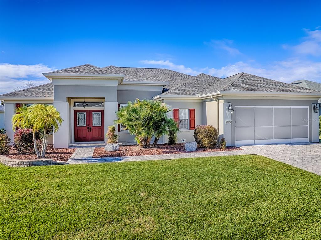 A single-story suburban house with a gray exterior, red front doors, and a paved driveway — 13324 SE 91ST COURT ROAD, SUMMERFIELD, FL