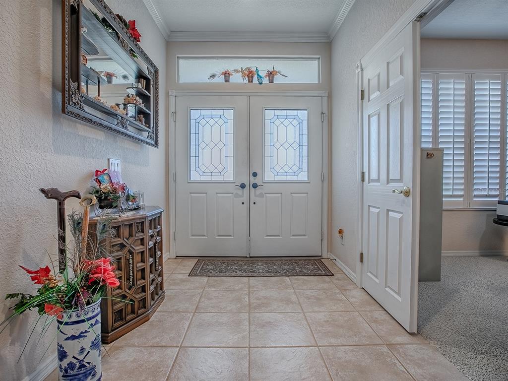 An entryway features tile flooring, double front doors with glass inserts, and a wooden console table — 13324 SE 91ST COURT ROAD, SUMMERFIELD, FL