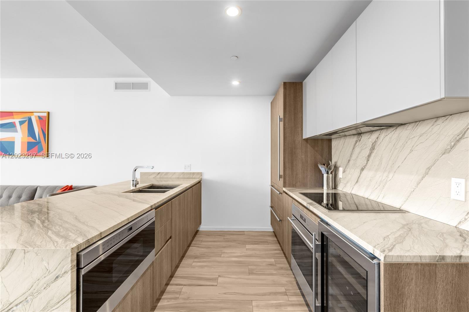 A modern kitchen features wood cabinetry, stone countertops, and integrated stainless steel appliances — 801 S Miami Ave # 4104, Miami FL 33130, MIAMI, FL