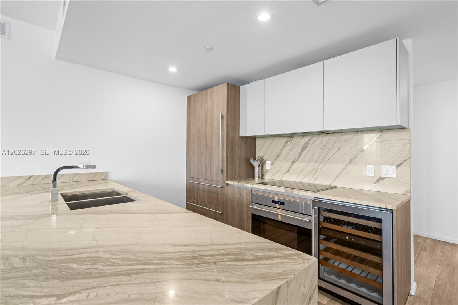 A modern kitchen features stone countertops, wood-toned cabinetry, and stainless steel appliances — 801 S Miami Ave # 4104, Miami FL 33130, MIAMI, FL