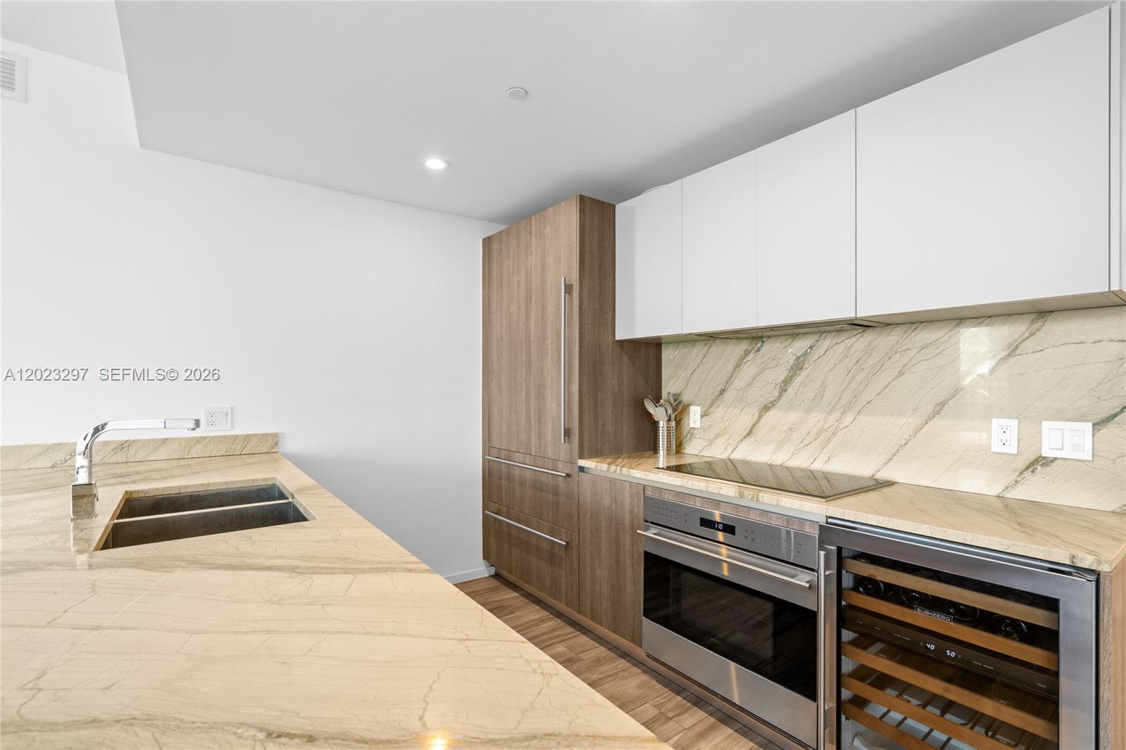 A modern kitchen features wood-paneled cabinetry, white upper cabinets, and marble countertops and backsplash — 801 S Miami Ave # 4104, Miami FL 33130, MIAMI, FL