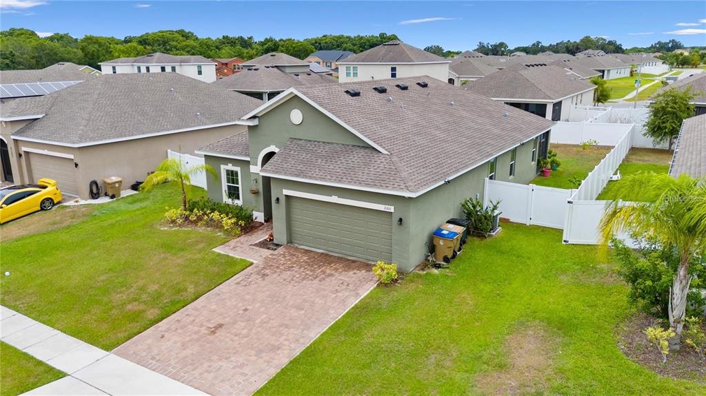 An aerial view of a green suburban house with a brick driveway and white fencing — 2160 PRESTON LANE, KISSIMMEE, FL