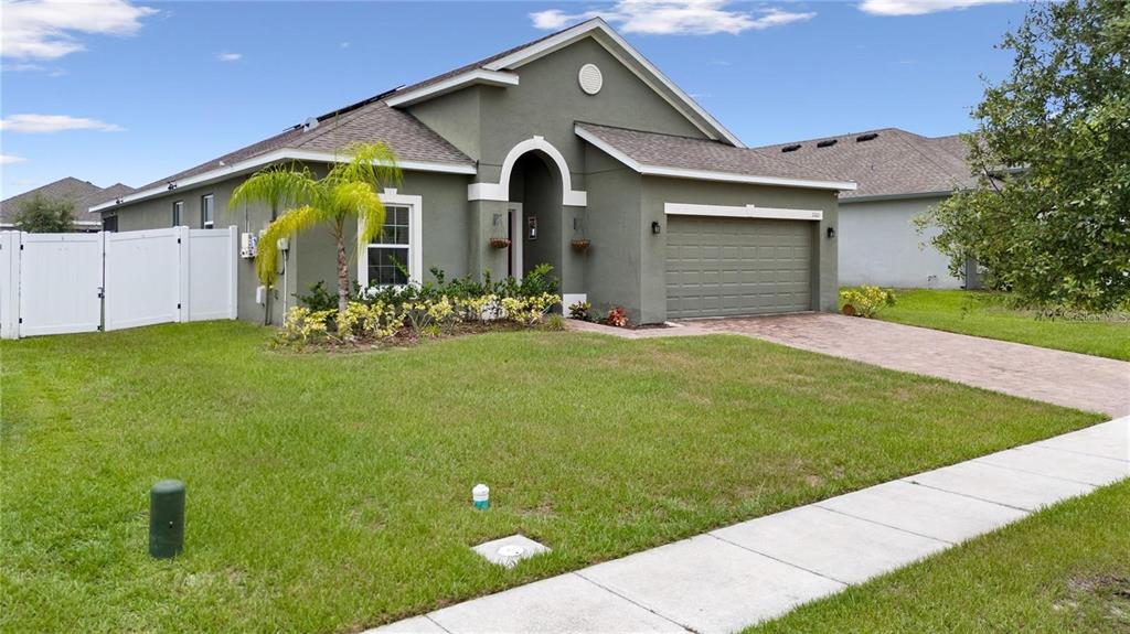 A single-story house with a green stucco exterior, a two-car garage, and a white fence — 2160 PRESTON LANE, KISSIMMEE, FL