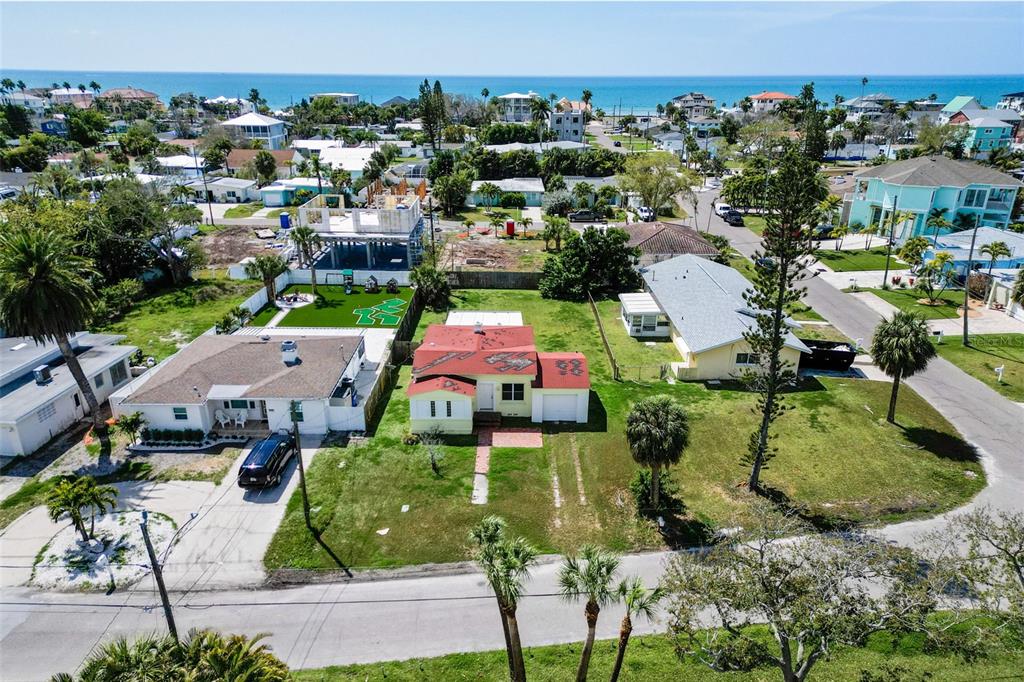 An aerial view shows a yellow house with a red roof surrounded by residential properties — 15822 REDINGTON DRIVE, REDINGTON BEACH, FL