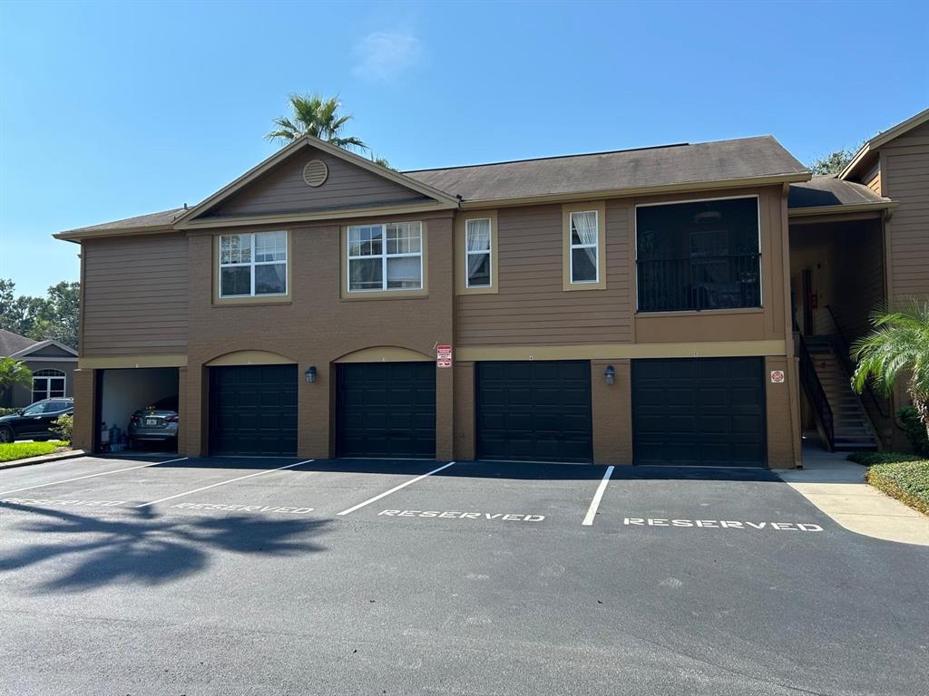 A two-story apartment building features four ground-level garages and a staircase leading to upper units — 400 SUMMIT RIDGE PLACE UNIT 216, LONGWOOD, FL